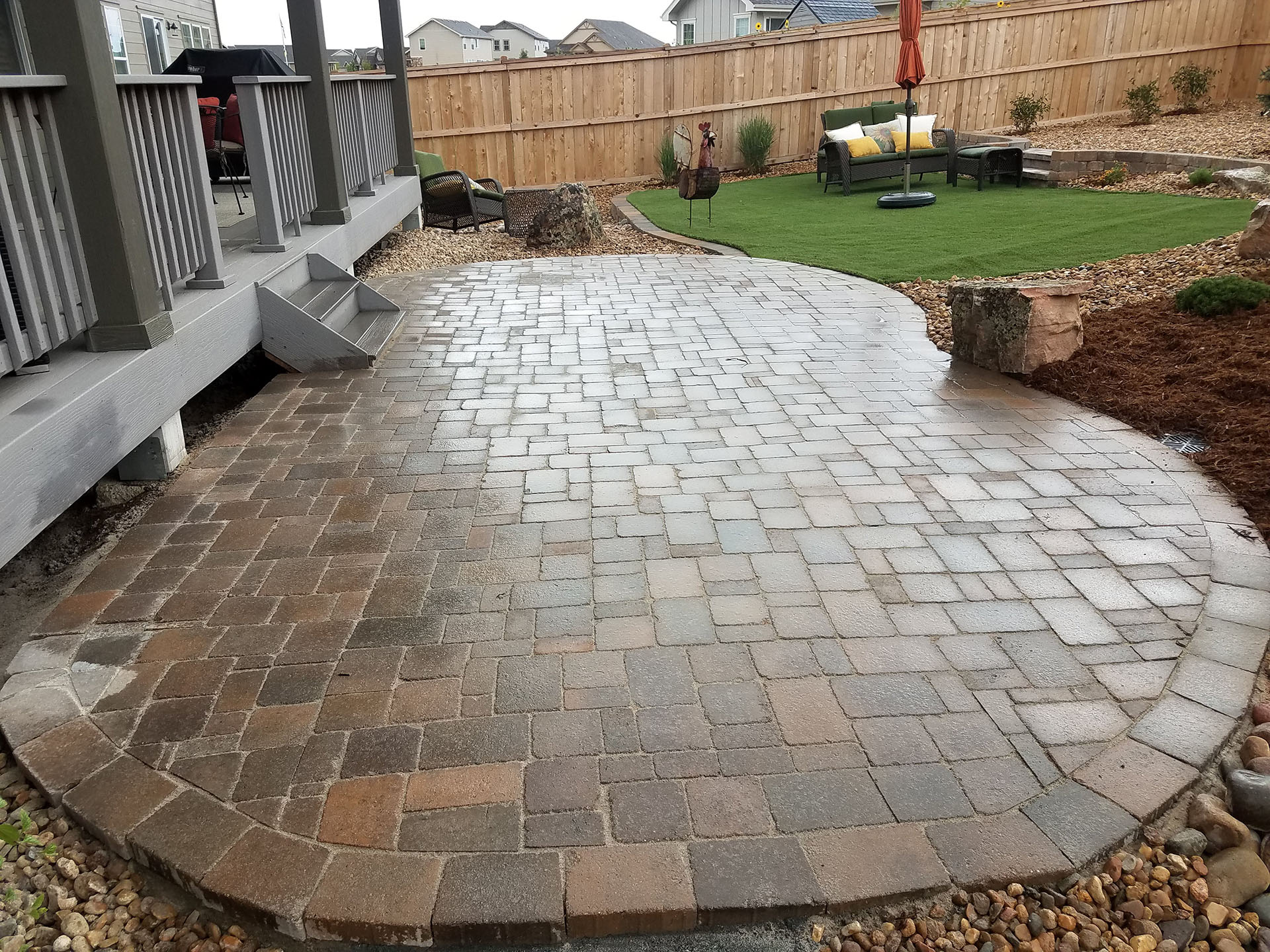 Curved paver patio with landscaped backyard